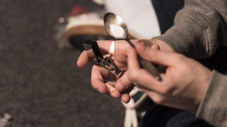 selective focus of junkie man boiling heroin in spoon on lighterの写真素材
