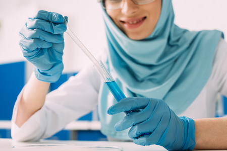 cropped view of female muslim scientist holding test tube and pipette in laboratoryの写真素材
