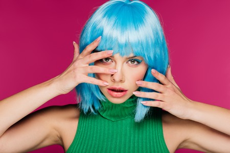 beautiful young woman gesturing and posing in blue wig, isolated on pinkの写真素材