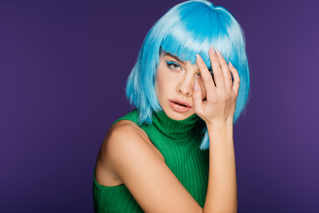 sensual young woman posing in blue wig and green turtleneck, isolated on purpleの写真素材
