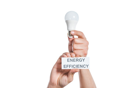 cropped view of man holding fluorescent lamp and paper card with lettering isolated on white, energy efficiency conceptの写真素材