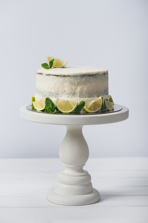 cake decorated with slices of lime on stand isolated on whiteの写真素材