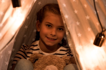 Smiling cute kid with teddy bear looking at camera