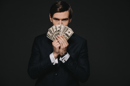 businessman holding dollar banknoted in hands isolated on blackの写真素材