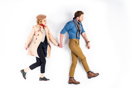 Elegant couple holding hands while walking on white background