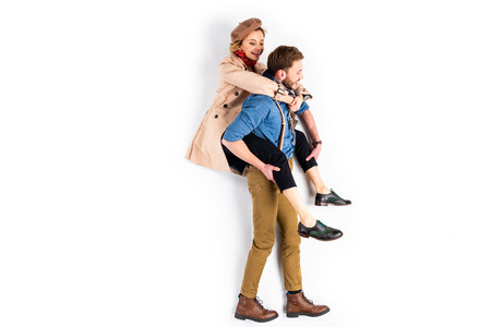 Man in brown pants carrying girlfriend piggyback on white background