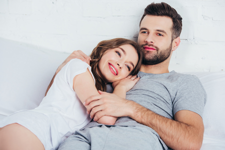 adult loving woman gentle embracing man in bedの写真素材