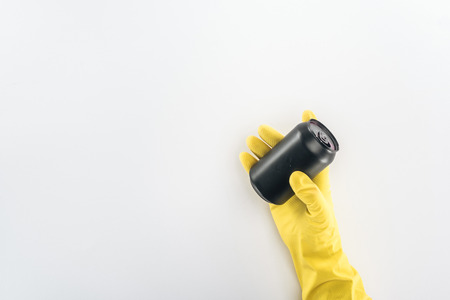 Cropped view of man in yellow rubber gloves holding empty black can on grey backgroundの写真素材