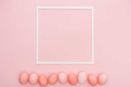 top view of traditional pastel easter eggs with empty frame isolated on pink