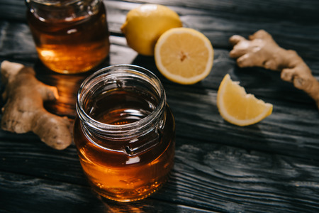 selective focus of  tea in glass jar on wooden table with ginger roots and lemonsの写真素材