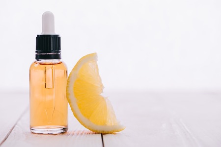 cbd oil in bottle with dropper and lemon slice on wooden surface isolated on whiteの写真素材