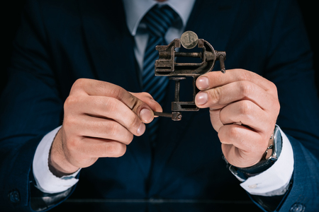 cropped shot of businessman holding iron vise tool with russian ruble coinの写真素材