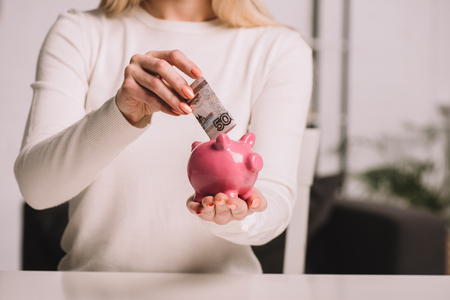 cropped shot of woman putting russian rubles into piggy bank, savings conceptの写真素材