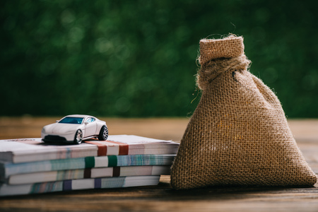 close-up view of sackcloth bag with money, rubles banknotes and model car on wooden tableの写真素材