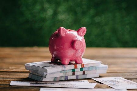 close-up view of stacked rubles banknotes and pink piggy bank on wooden tableの写真素材