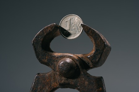 close-up view of iron vise tool with one ruble coin isolated on grey
