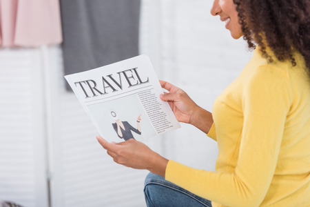 partial view of smiling girl reading travel newspaper at homeの写真素材
