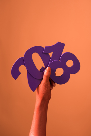 partial view of coral colored female hands with violet paper cut 2018 numbers on coral background, color of 2019 conceptの写真素材