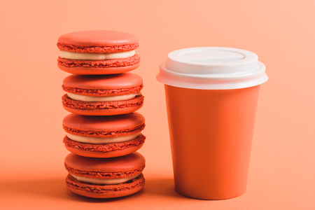 stack of coral macarons and paper cup on coral background, color of 2019 conceptの写真素材