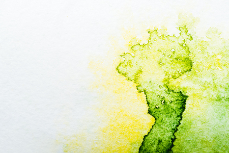 top view of yellow and green watercolor spills on white paperの写真素材