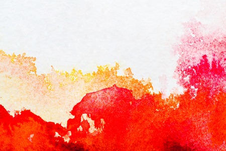 top view of red and orange watercolor spills on white paperの写真素材
