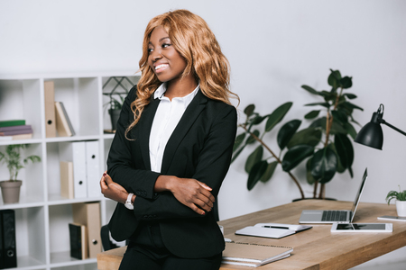 african american businesswoman with crossed arms in modern officeの写真素材