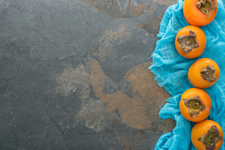 top view of whole persimmons on blue cloth with copy spaceの写真素材