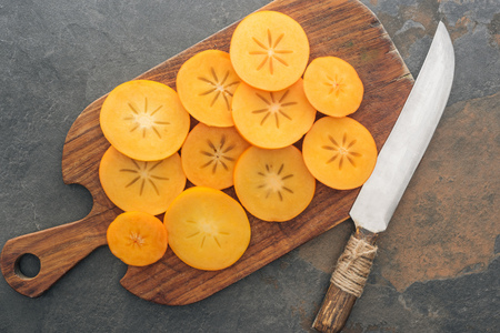 top view of sliced orange persimmons on cutting board with knifeの写真素材