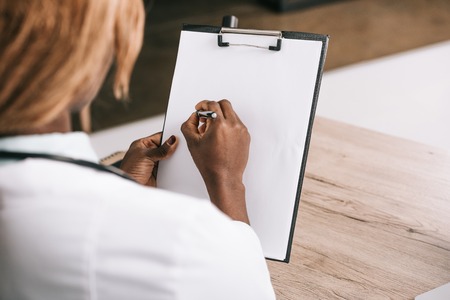 cropped view of african american scientist writing on paper