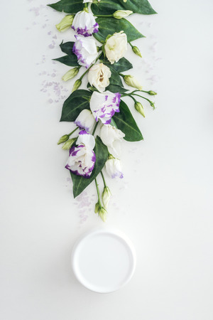 top view of composition with purple and white eustoma, beauty cream in bottle on white backgroundの写真素材