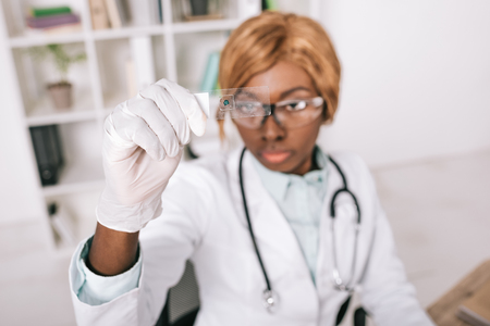 selective focus of sample in hand of concentrated african american scientistの写真素材
