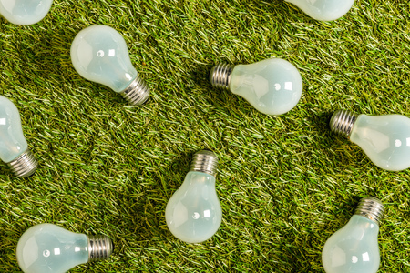 top view of modern fluorescent lamps on green grass, energy efficiency concept