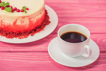 close up of cake decorated with currants and mint leaves near cup of coffeeの写真素材