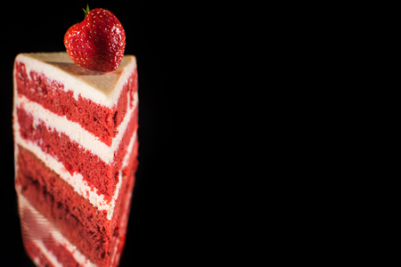 piece of white and red cream cake with berry isolated on blackの写真素材