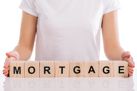 cropped view of woman holding wooden cubes with mortgage lettering isolated on whiteの写真素材