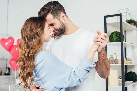 selective focus of tenderly smiling couple dancing on st valentine day at homeの写真素材