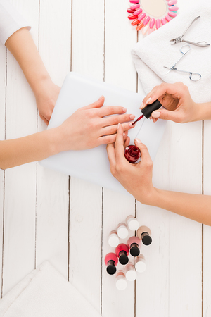Top view of manicurist applying red nail polishの写真素材