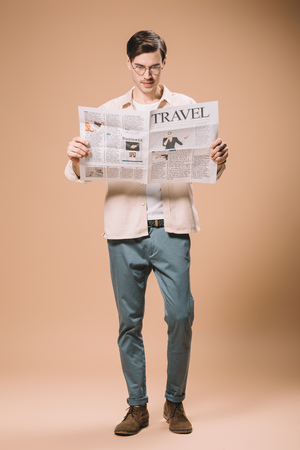 handsome man reading travel newspaper on beige backgroundの写真素材