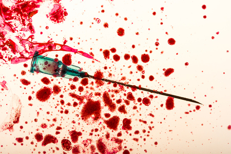 Studio shot of medical needle and blood dropsの写真素材