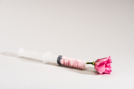 Studio shot of pink flower, syringe and pills on greyの写真素材