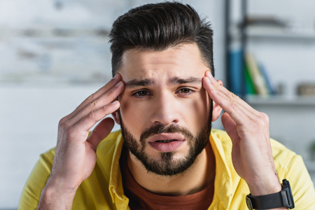 Close up of bearded businessman man touching head at workplaceの写真素材