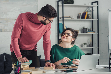 attractive woman in glasses looking at colleague in officeの写真素材