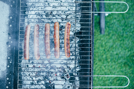 top view of tasty grilled sausages on bbq grill grade on green grass backgroundの写真素材