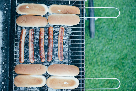 top view of tasty hot dogs grilling on bbq grill grade on green grass backgroundの写真素材