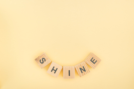 top view of shine lettering made of wooden blocks on yellow backgroundの写真素材