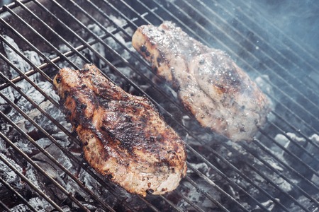 selective focus of juicy steaks grilling on hot coals with smokeの写真素材