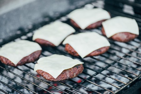 selective focus of fresh burger cutlets with cheese grilling on bbq gridの写真素材