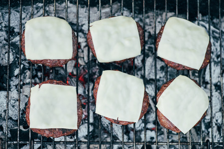 top view of delicious burger cutlets with cheese grilling on bbq grid