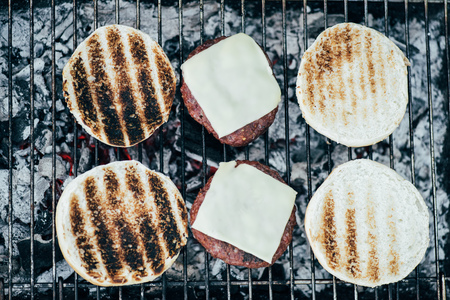 top view of delicious fresh burgers ingredients grilling on bbq gridの写真素材