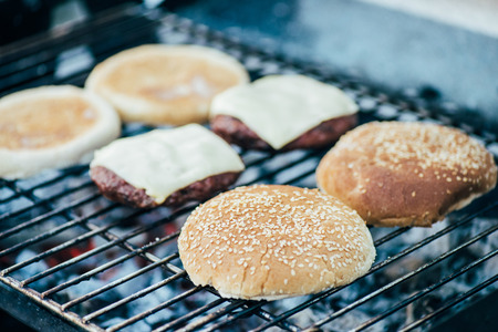 selective focus of delicious fresh burgers ingredients grilling on barbecue gridの写真素材